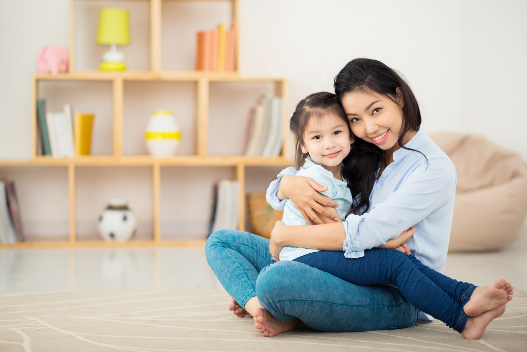 Portrait of happy young woman and her daughter hugging and looking at the camera