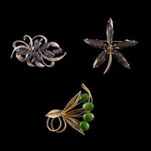 A lot of three brooches with green stone in gold, starts at P 1,800.