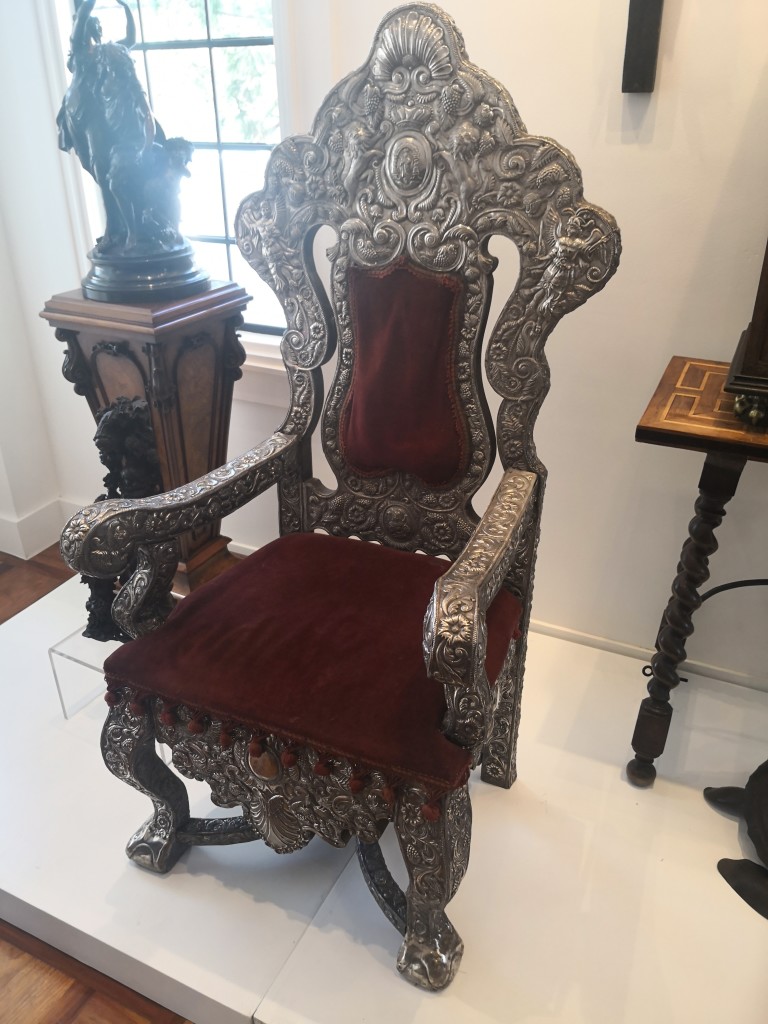 The detailed high-back armchair in wood with silver overlay is a thing of beauty